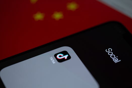 Close-up of TikTok app icon on a smartphone, set against a Chinese flag background.