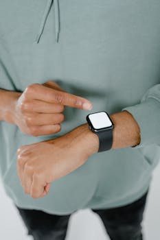 Close-up of a person pointing at a wrist smartwatch, emphasizing technology and modern lifestyle.