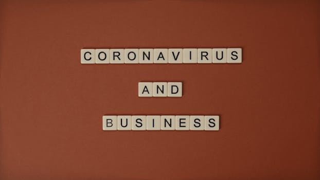 Scrabble tiles spelling 'Coronavirus and Business' on an orange background, illustrating pandemic impact.