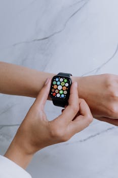 Hands interacting with a smartwatch on a marble background.
