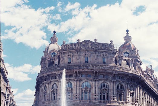 Majestic baroque building with fountain under a bright summer sky in a bustling city square.