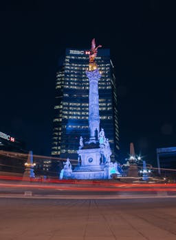 Night view of the Angel of Independence in Mexico City with light trails and illuminated buildings.